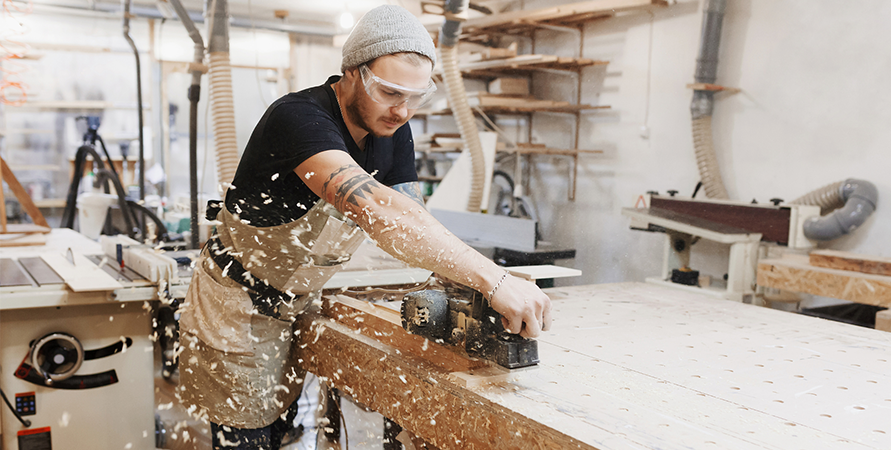 Imagen de un carpintero cortando una tabla con una cierra eléctrica