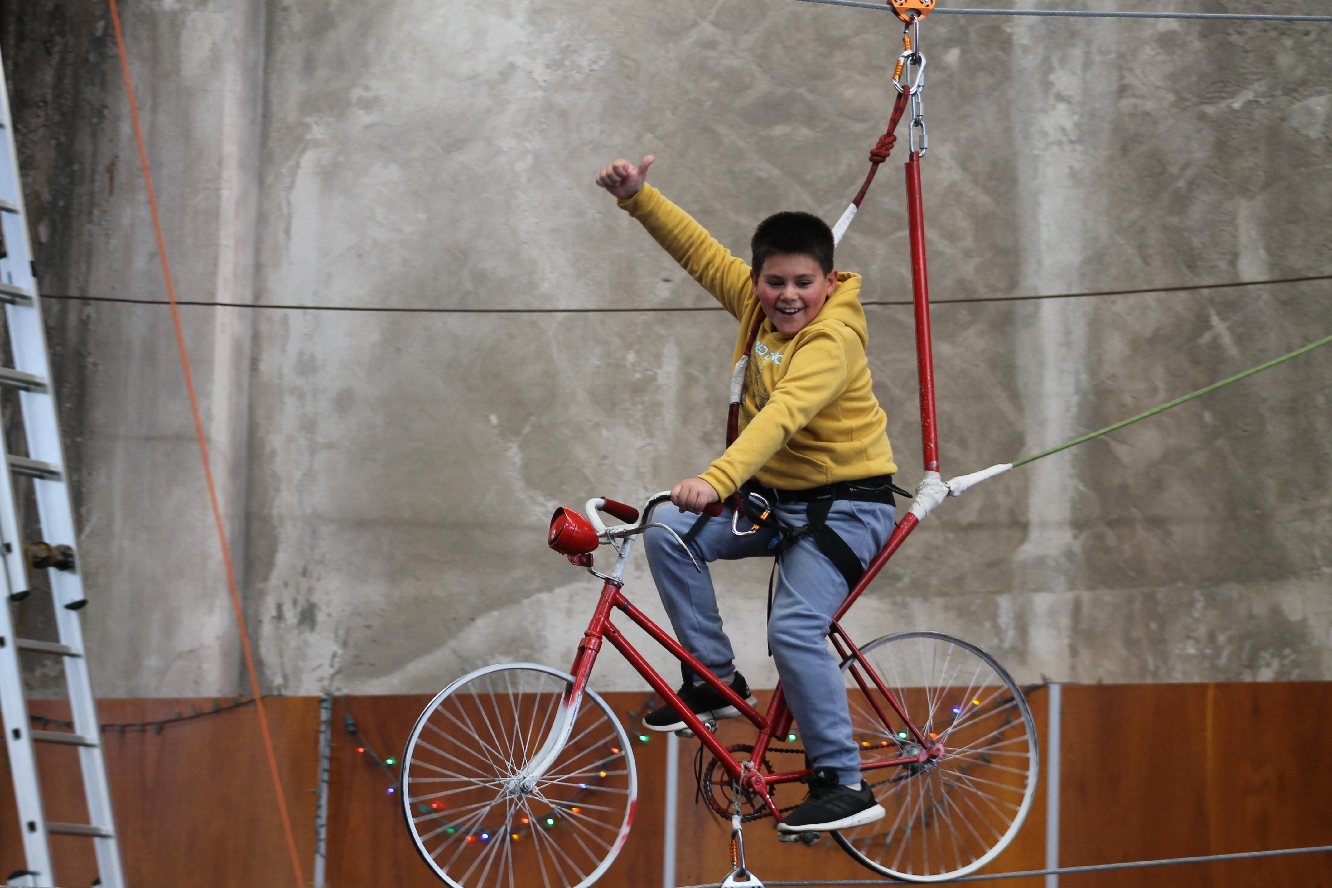 Jornada 3: Niño pedaleando y saludando en la "bici voladora"